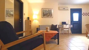 Una sala de estar con sofá, una mesita, una lámpara y un comedor con sillas y una mesa.