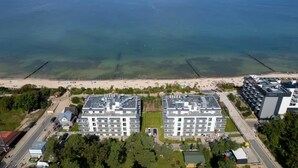 A coastal hotel with two main buildings, a beach in the background, and a clear view of the sea. - Modern Studio in Mielno | View of the Sea and Parking Lot (Mielno)
