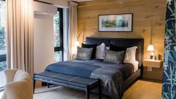 Quarto moderno com uma cama grande, luminárias de cabeceira, um banquinho e vista pela janela.