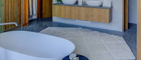 A modern bathroom with a freestanding bathtub, two sinks, and a wooden vanity.