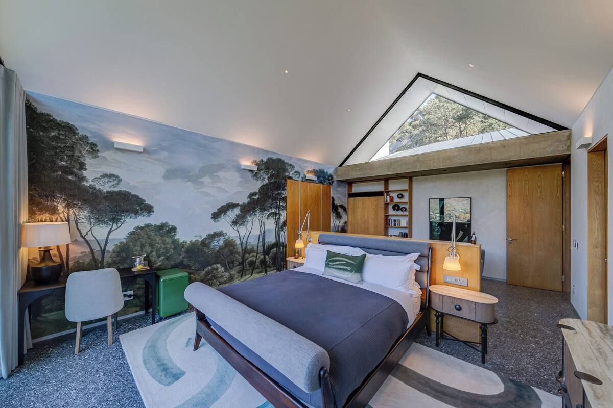 Una camera da letto moderna con un letto grande, una scrivania e un murale raffigurante una scena di foresta.
