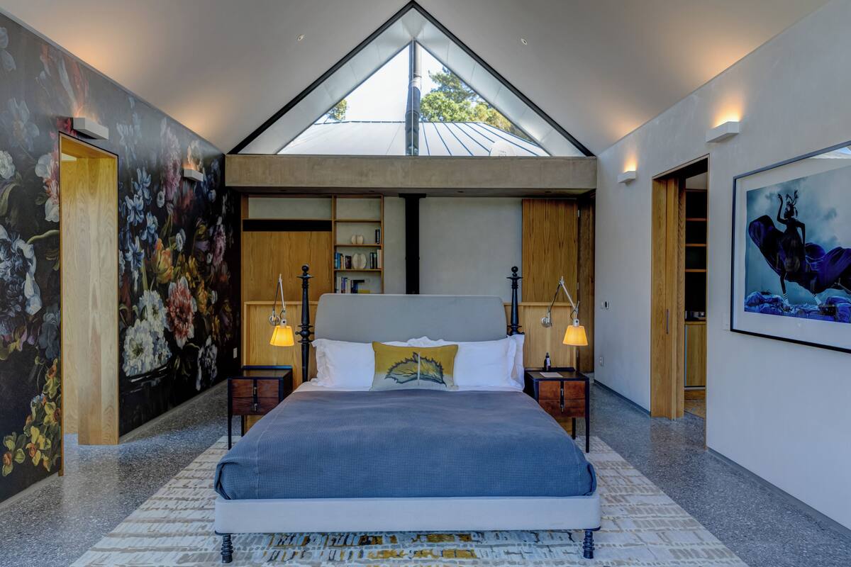 Una camera da letto moderna con un letto grande, una finestra a lucernario, un murale floreale e un quadro appeso al muro.