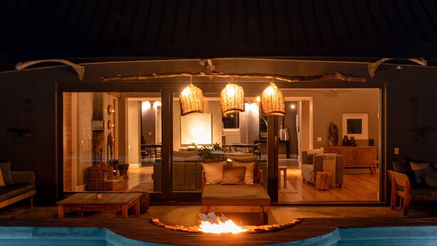 Un área de piscina interior moderna con chimenea, mobiliario de madera y un espacio interior bien iluminado.