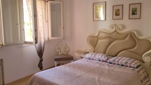 A bedroom with a large bed, a nightstand, a bedside table, a window with curtains, and a wall with three framed pictures. - Appartamento Nuovo A Chioggia Vista Laguna (Chioggia)