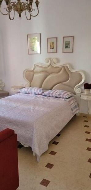 Un dormitorio con una cama grande, una araña y cuadros enmarcados en la pared.