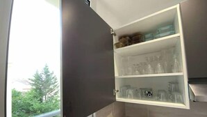 Ett kök med ett inbyggt skåp som innehåller glas och burkar.