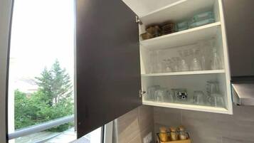 A kitchen with a built-in cabinet containing glassware and jars.