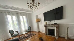 Ett vardagsrum med en öppen spis, en tv och en kristallkrona.