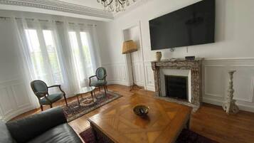 A living room with a fireplace, a television, and a chandelier.