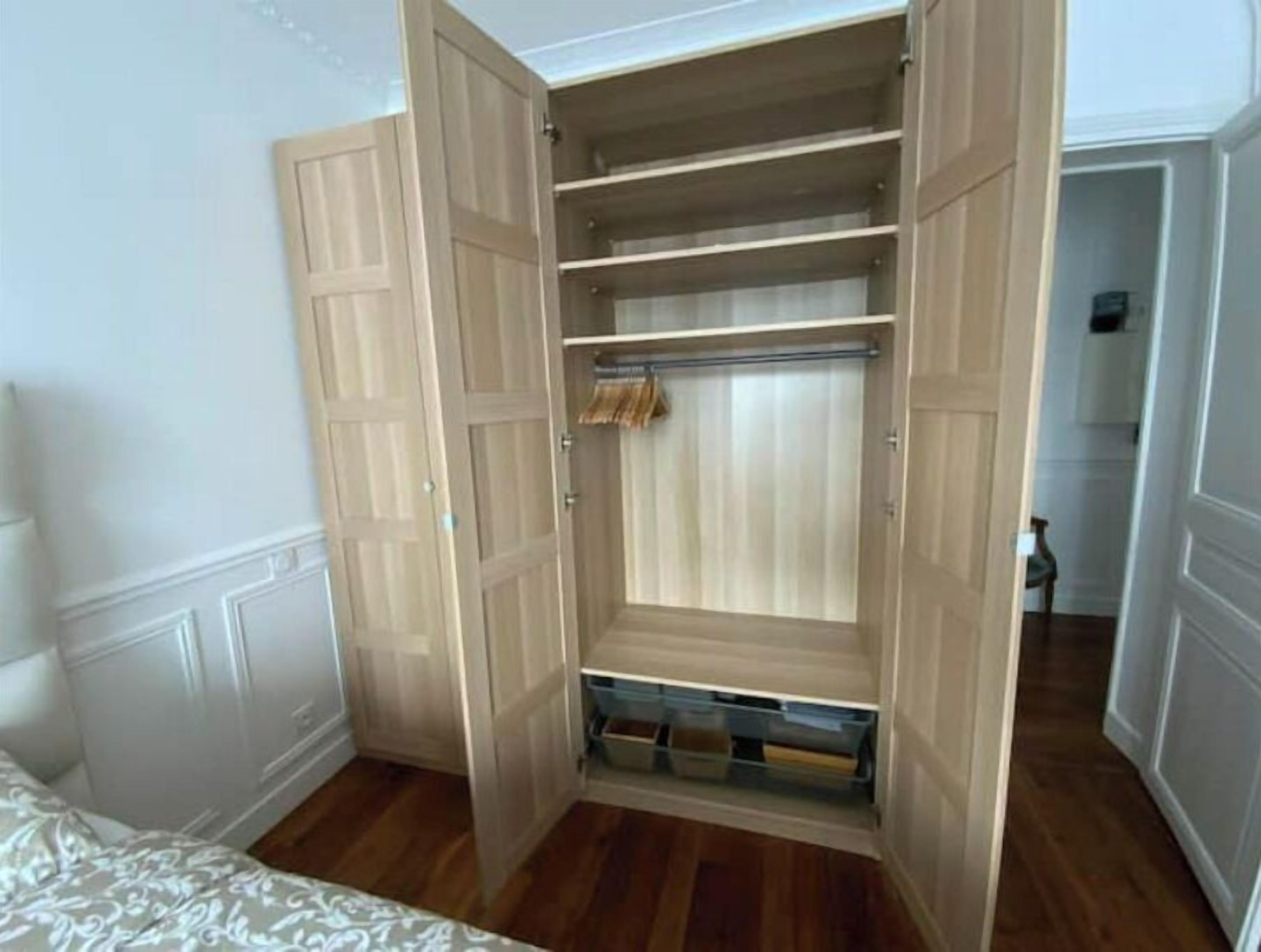 Un vestidor con puertas de madera, varios estantes y espacio para colgar ropa.