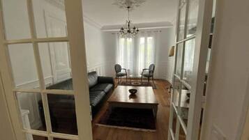 A room with a dark leather sofa, a wooden coffee table, and a chandelier.