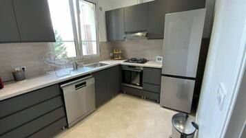 A modern kitchen with dark cabinetry, a stainless steel refrigerator, and a gas stove.