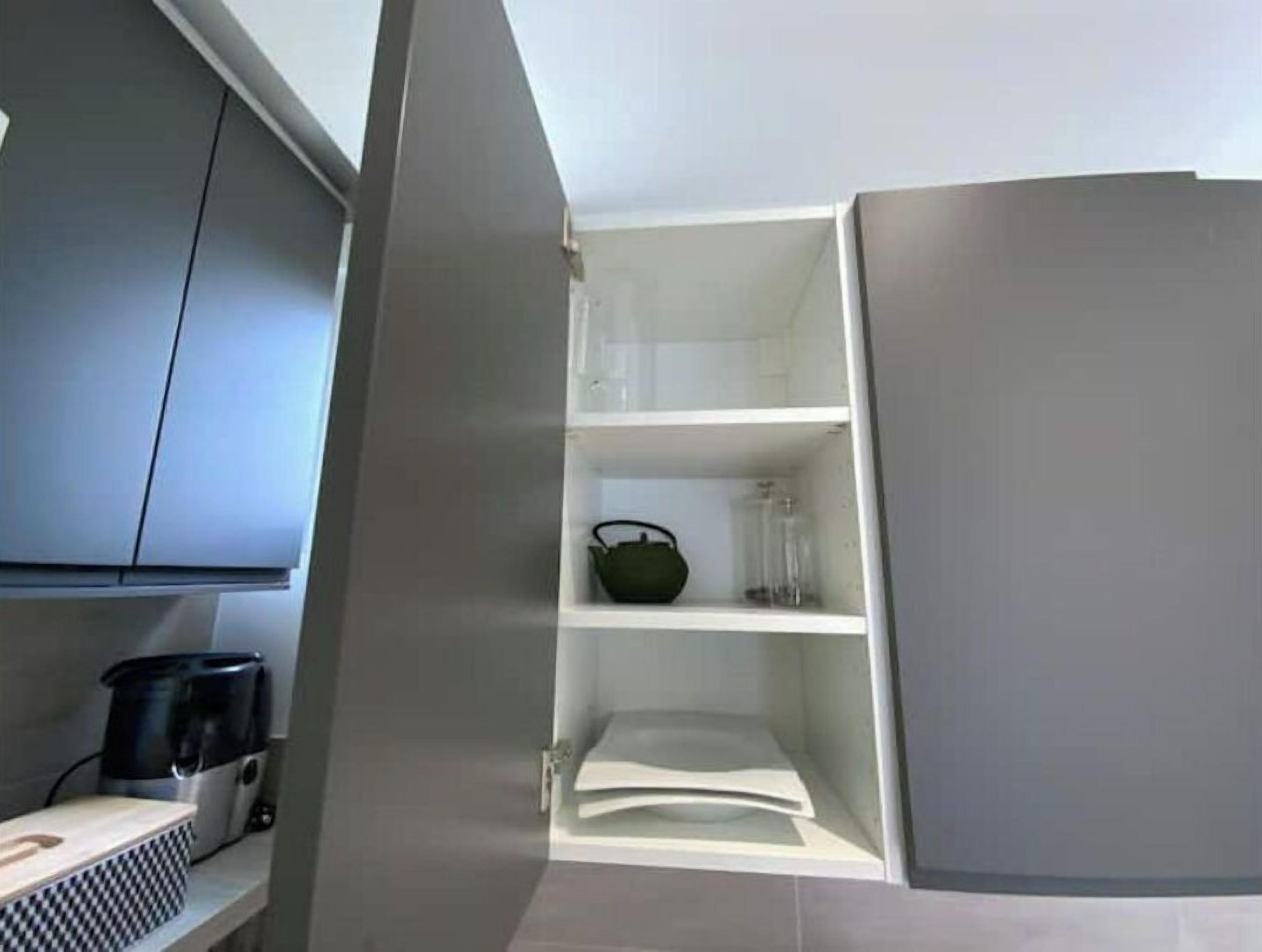 A kitchen with grey cabinets, a coffee maker, and a kettle on the counter.