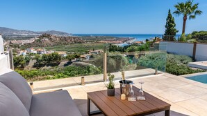 A terrace with a wooden table, a potted plant, and a bottle of champagne. - Villa Las Arenas with private heated pool (Salobreña)