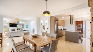 A modern kitchen with a central island, wooden dining table, and chairs. - Villa Las Arenas with private heated pool (Salobreña)