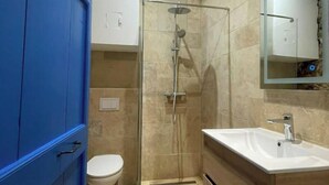 Ein modernes Badezimmer mit einer Glaskabine zur Dusche, einer weißen Toilette und einem hölzernen Waschtisch.