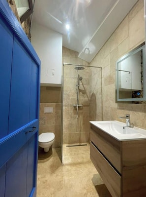 Une salle de bain moderne avec une douche à parois de verre, des toilettes blanches et un meuble-lavabo en bois avec un évier.
