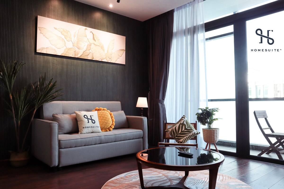 A modern living room with a grey sofa, a round coffee table, and a large window with curtains.