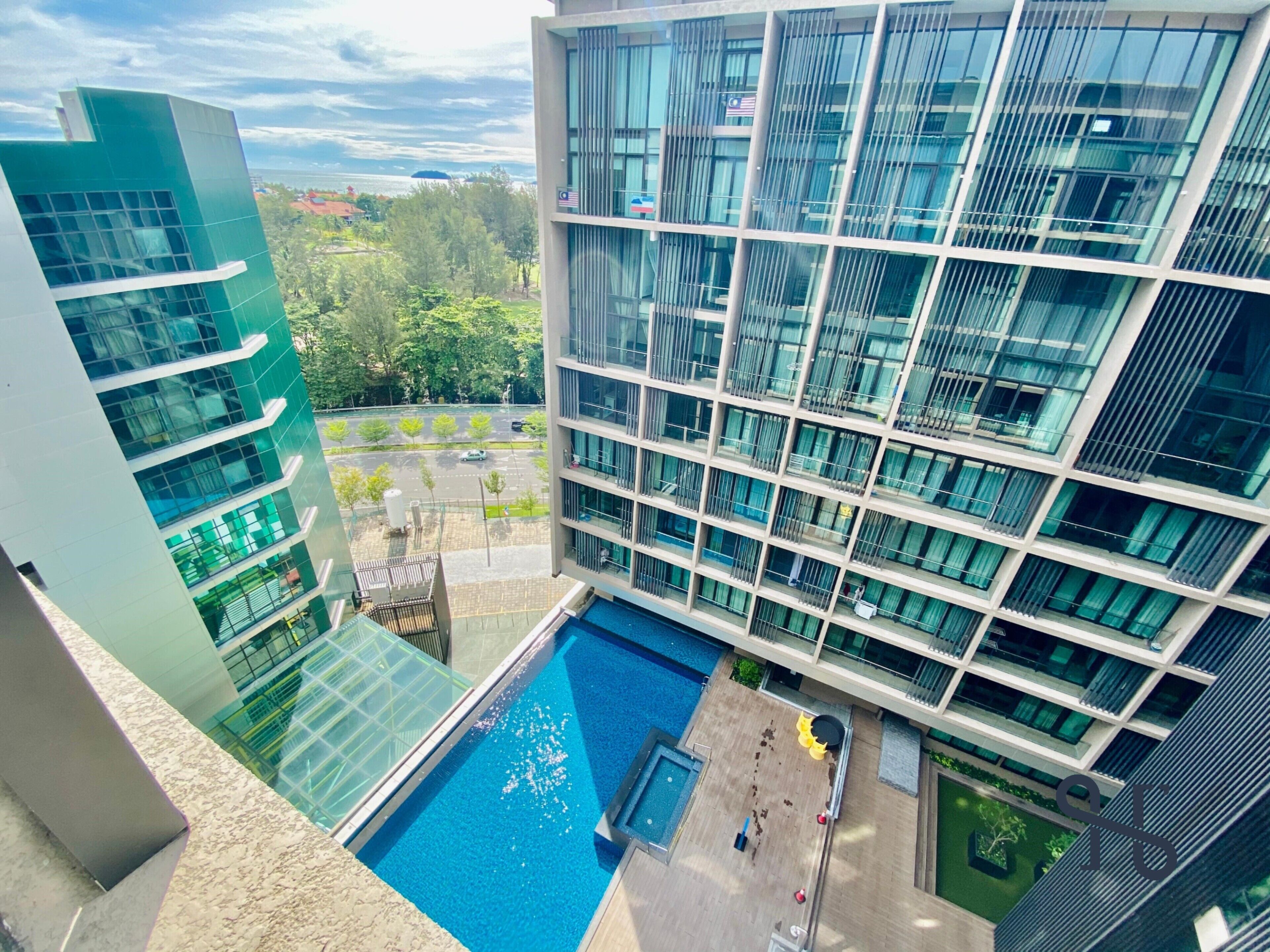 A modern building with a rooftop pool, large windows, and a view of the surrounding area.