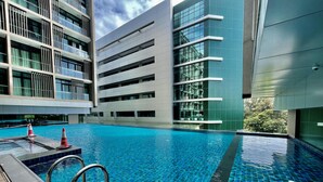 A modern hotel with a large indoor swimming pool, multiple floors, and a contemporary architectural design. - Homesuite’ Home @ Riverson SOHO (Kota Kinabalu)