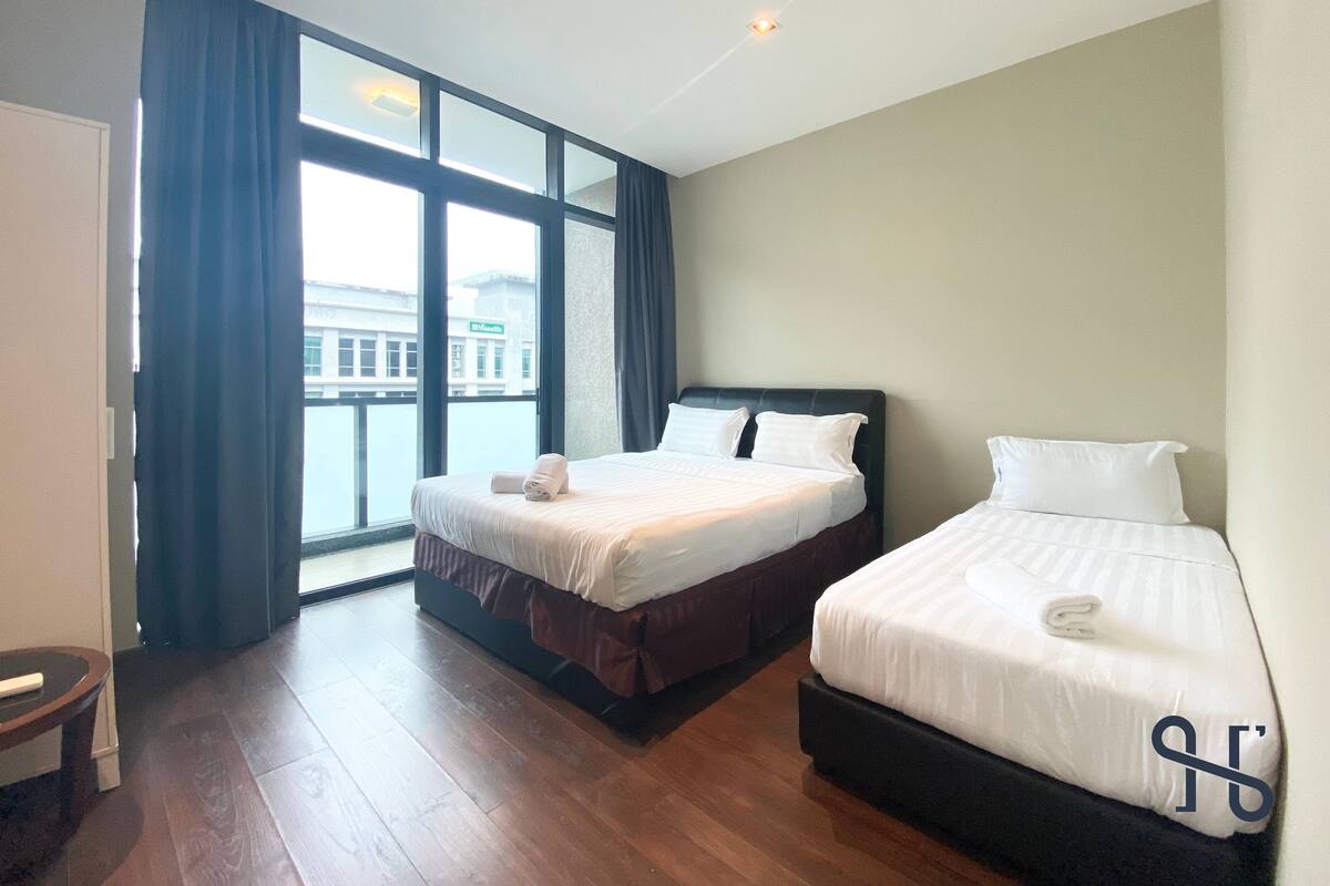 A hotel room with two beds, a large window, and a view of a building outside.