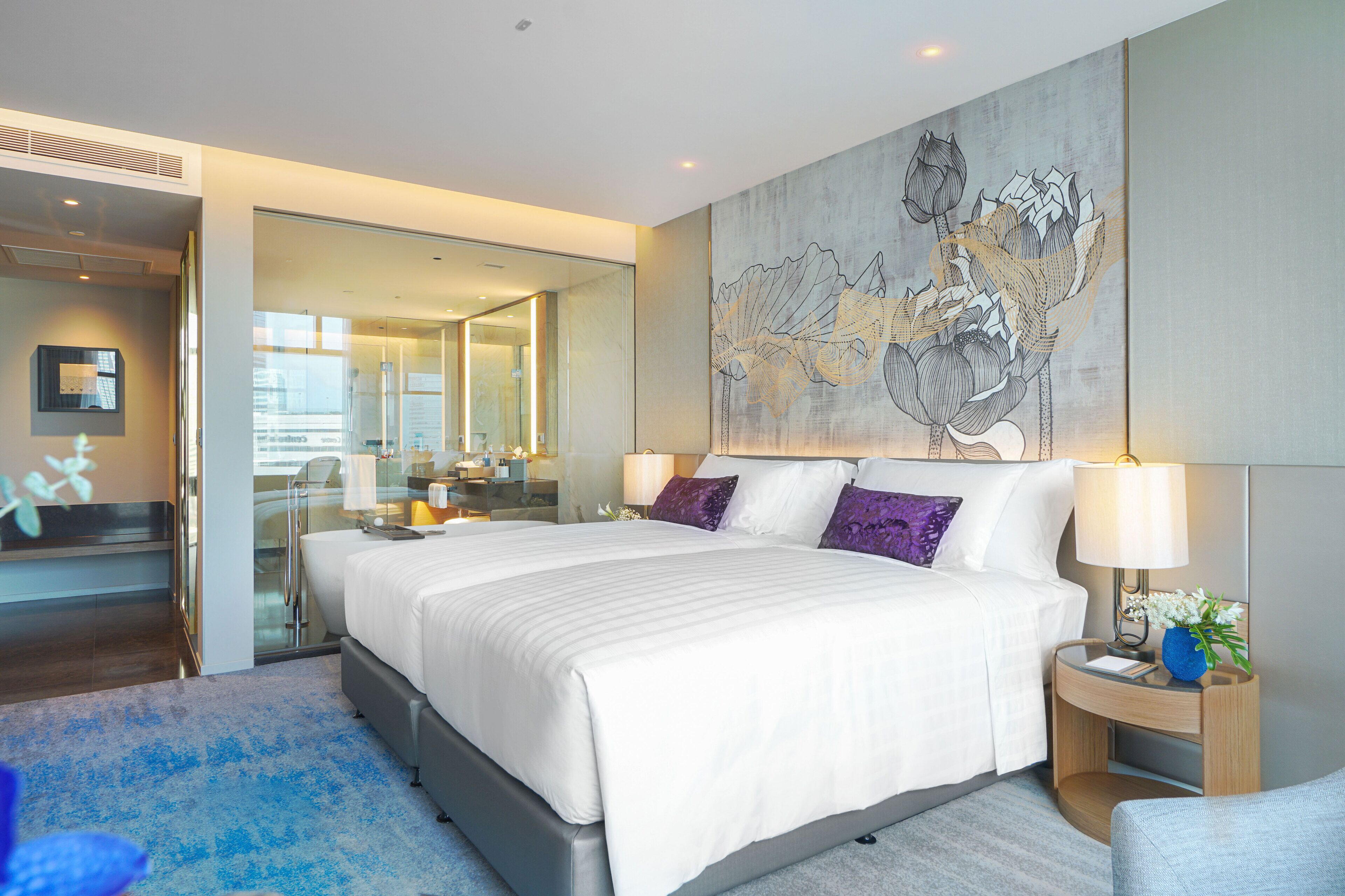 Een moderne hotelkamer met een groot bed, een glazen scheidingswand en een groot bloemwerk aan de muur.