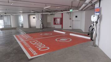A parking area with electric vehicle charging stations, a red floor marking, and a sign indicating an exit.