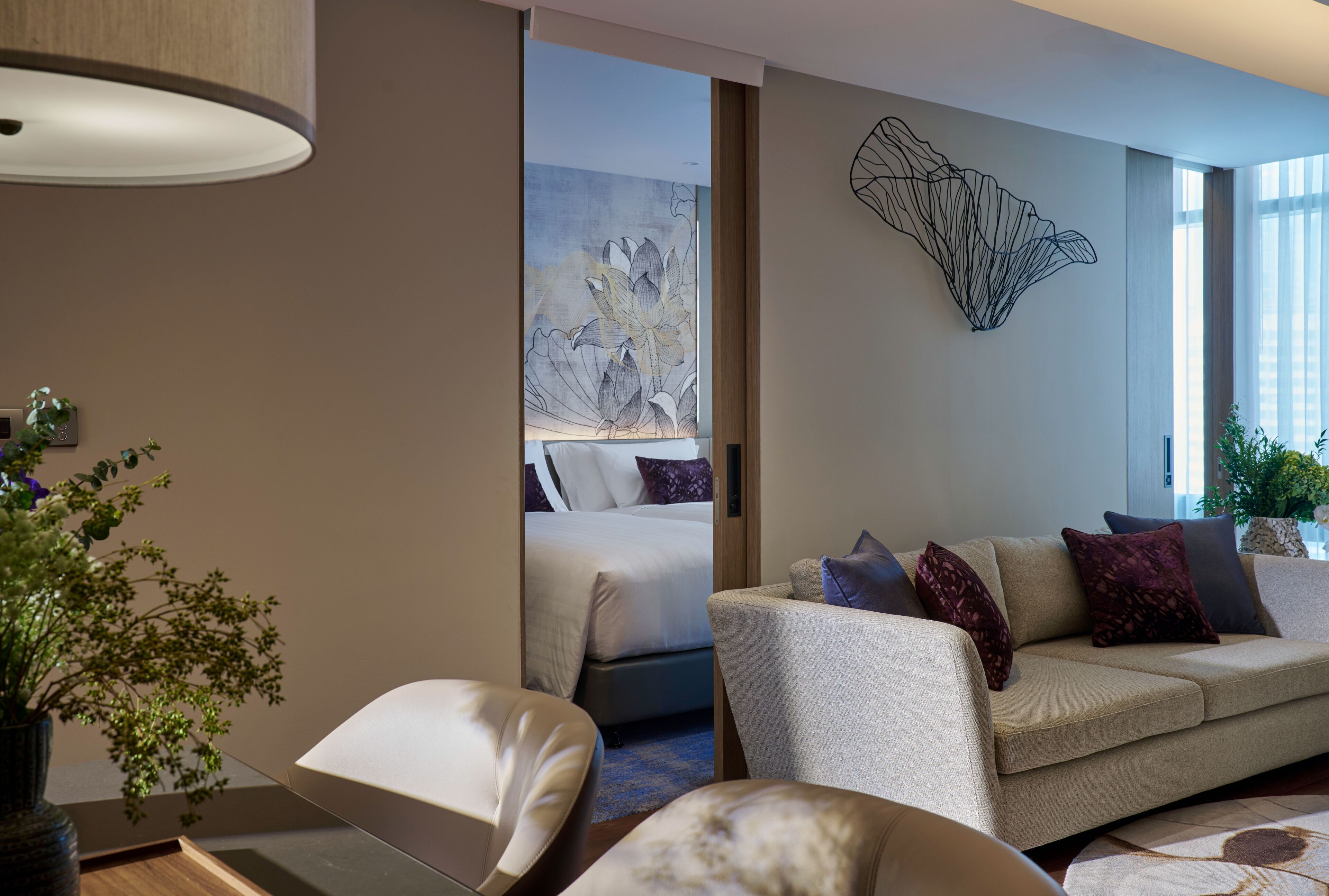 Een moderne hotelkamer met een bank, een stoel, een bed en een groot abstract kunstwerk aan de muur.