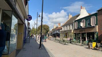 A pedestrian street lined with shops and cafes, featuring a brick pavement and traditional architecture.