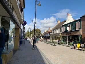 A pedestrian street lined with shops and cafes, featuring a brick pavement and traditional architecture.