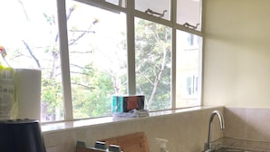 Cozinha com pia, máquina de café e janela com vista para árvores.