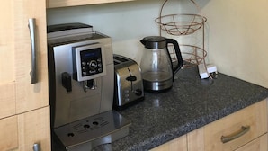 Cozinha com armários de madeira, cafeteira, torradeira e chaleira na bancada.