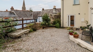 A courtyard with a gravel ground, a wooden fence, and potted plants. - 2 Old Talbot Cottages (Lostwithiel)