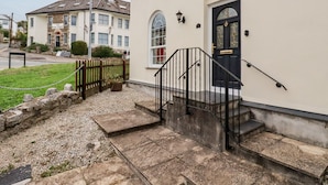 A building with a black door, a stone staircase, and a chain-link fence. - 2 Old Talbot Cottages (Lostwithiel)