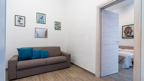 A modern room with a brown sofa, a wooden door, and a bed with a white bedspread. - 2978 La Dea Venere by Barbarhouse (Nardò)
