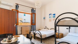 A room with bunk beds, a dining table with a coffee pot and pastries, a wooden cabinet, and a window with curtains. - 2978 La Dea Venere by Barbarhouse (Nardò)