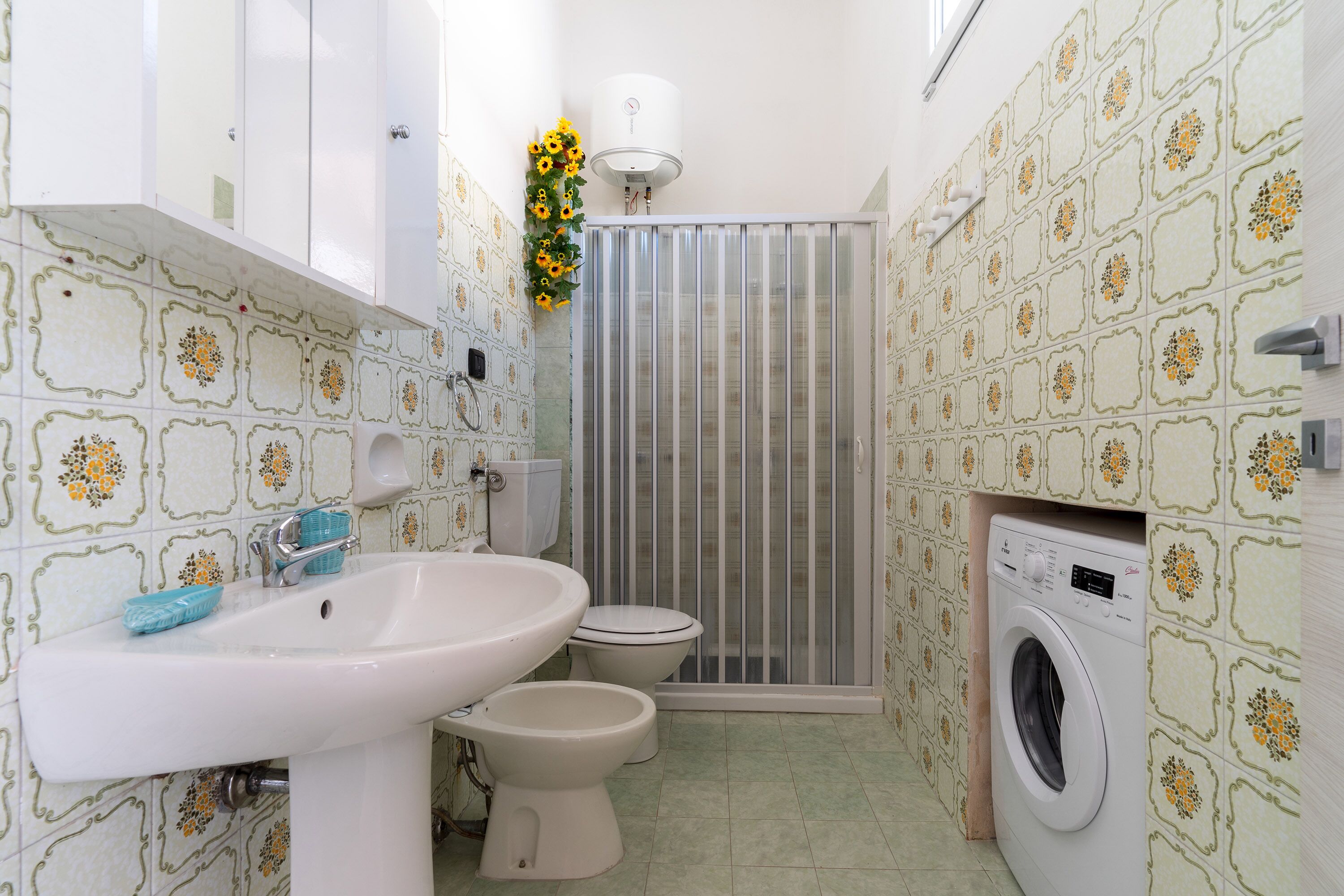 A bathroom with a sink, toilet, and washing machine.