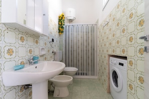 A bathroom with a sink, toilet, and washing machine.