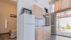 A modern kitchen with a refrigerator, microwave, and wooden cabinets. - 2978 La Dea Venere by Barbarhouse (Nardò)