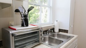 A kitchen with a built-in toaster oven, a sink, and a window with blinds.