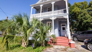 A two-story white house with a porch and a red front door.