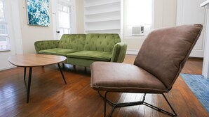 A room with a green sofa, a brown chair, and a wooden table.