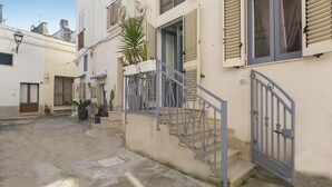 A narrow alleyway with a building featuring a metal staircase and a gate. - 2666 La Maisonnette - Appartamento 1 (Nardò)