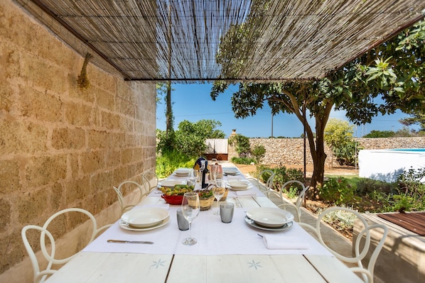 Enjoy a meal al fresco in this outdoor dining area, surrounded by lush greenery and comfortable seating.