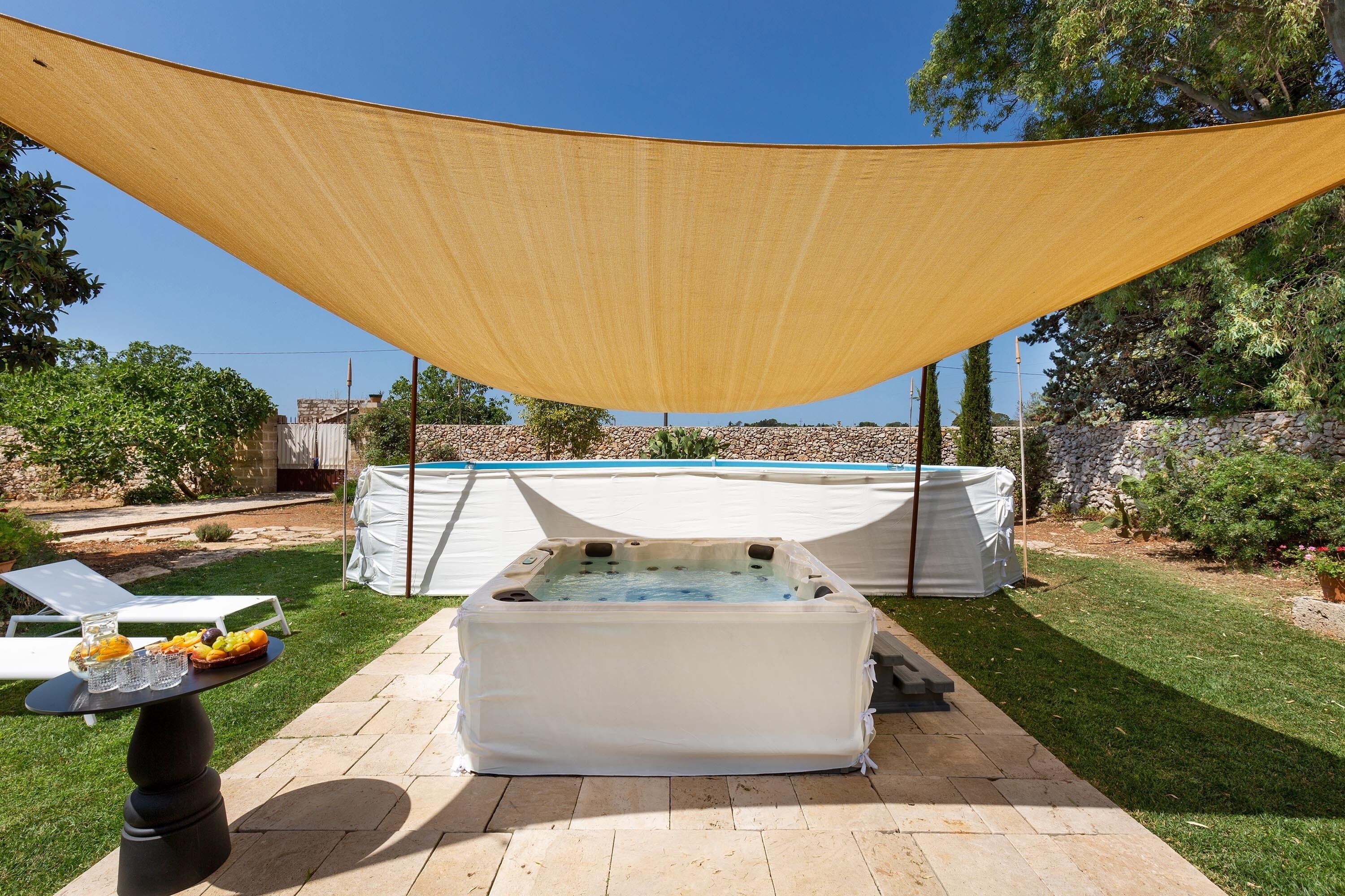 Ein Whirlpool und ein überdachter Tisch mit Getränken und Obst im Garten.