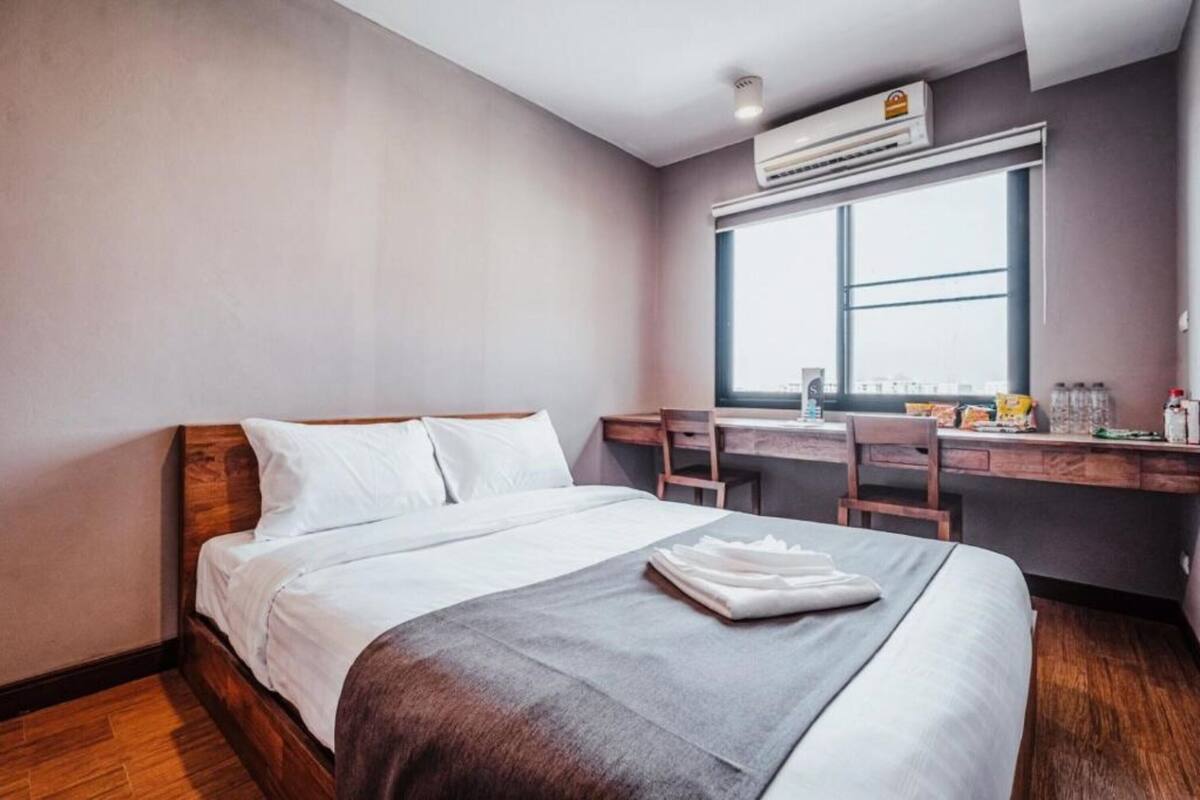A hotel room with a bed, a desk, and a window.