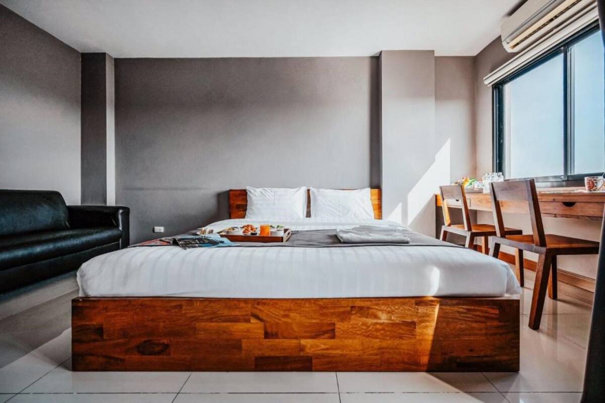 A modern hotel room with a wooden bed, a desk, and a chair.