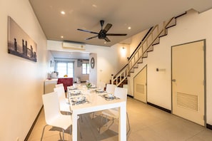 A dining area with a white table set for four, white chairs, a ceiling fan, and a staircase leading to another level. - 4 BR Townhouse in Great Location BSS (Hua Hin)