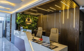 Una moderna recepción con un reloj, zona de estar y una pared con listones de madera verticales.