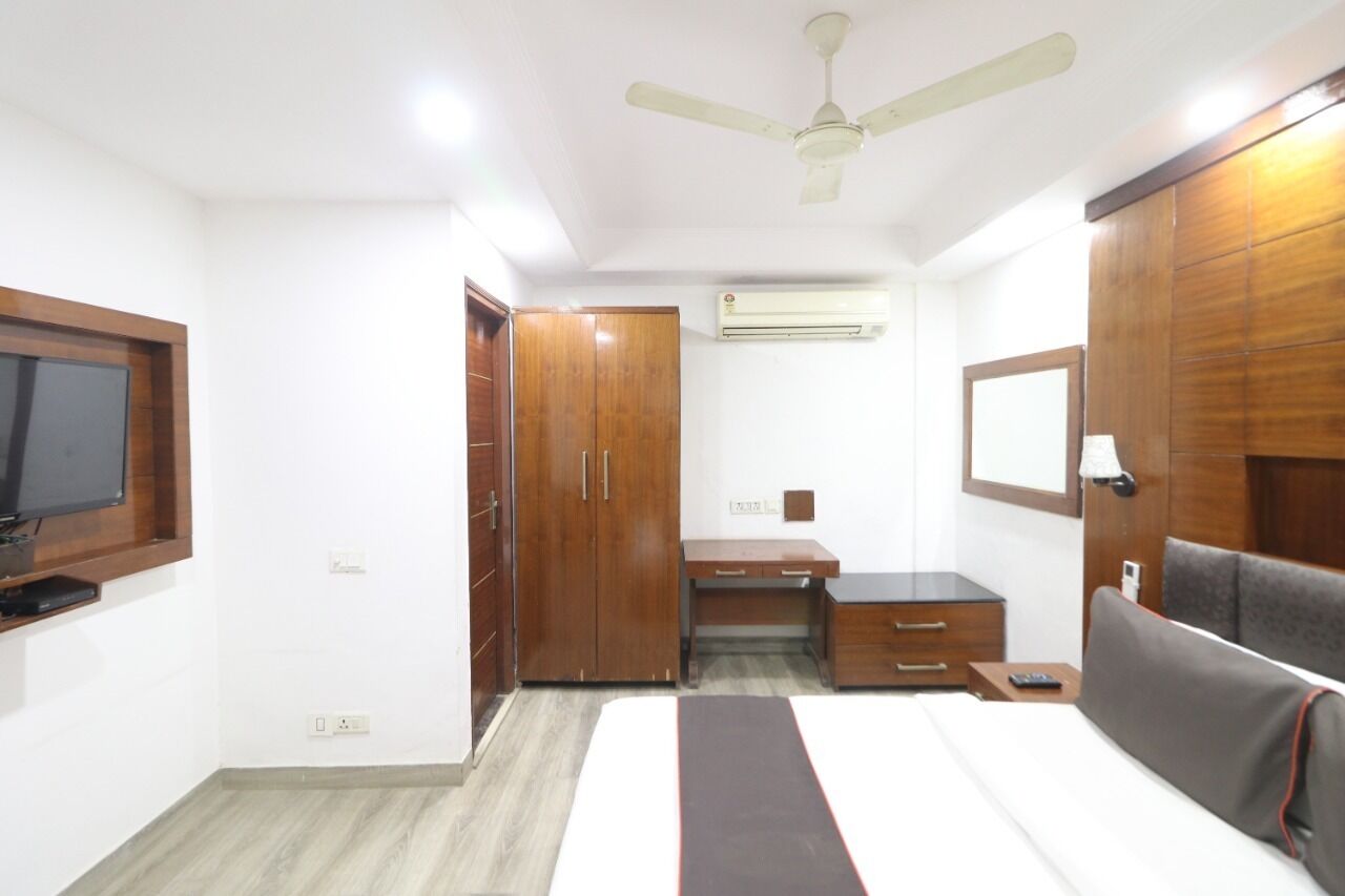 Ein Schlafzimmer mit Bett, Kleiderschrank, Schreibtisch und Fernseher.